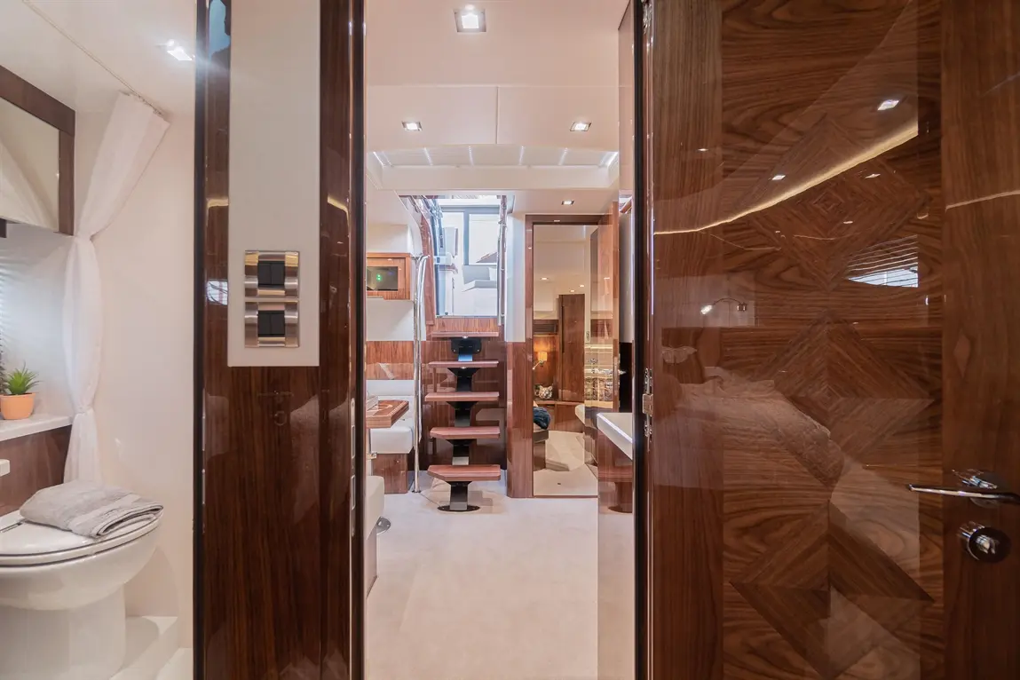 View from a doorway into a luxurious yacht interior featuring modern decor, stairs, and stylish wooden finishes.